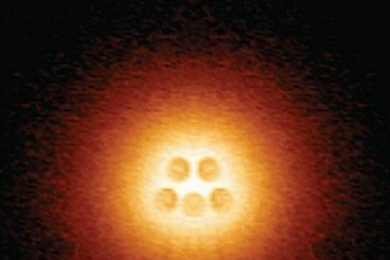 Scanning tunneling microscope image shows an artificial atomic nucleus on graphene, consisting of five pairs of calcium atoms (slightly darker circles at center), in an electron cloud that is on the verge of collapse.
