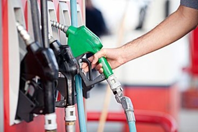 Photo of a hand holding a green gas handle at a gas station