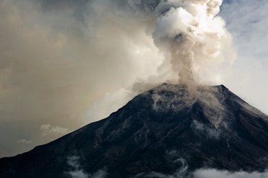 Photo of a volcano erupting with a smoke plume