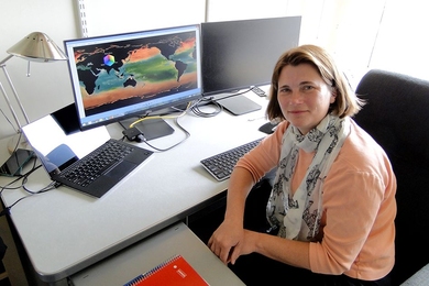 MIT research scientist Stephanie Dutkiewicz in her office with a display of her phytoplankton model simulation 