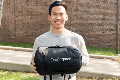 MIT Sloan School of Management student Vick Liu demonstrates how small and portable a compressed TravlerPack is — an important attribute for refugees carrying all of their possessions on foot. 