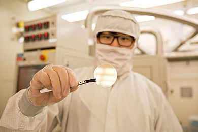 MIT postdoc Yuhao Zhang, handles a wafer with hundreds of vertical gallium nitride power devices fabricated from the Microsystems Technology Laboratories production line.
