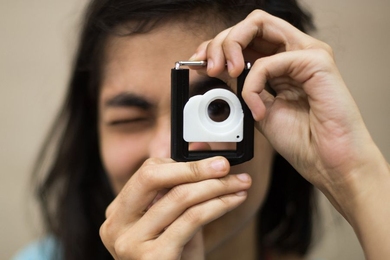 Person holds up device with lens near their eye