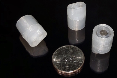 Three 3D-printed pumps next to a dime for size comparison