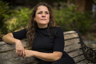 Portrait photo of Sarah Williams sitting on a park bench and gazing into the distance