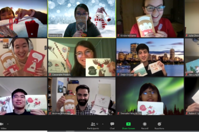 Partial screenshot of Sidney Pacific graduate community members smiling in a Zoom room and holding up written cards
