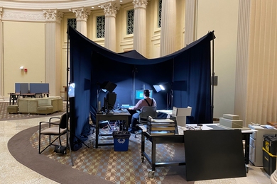 Photo of imaging equipment surrounded by a black tent inside a library room with ornate columns