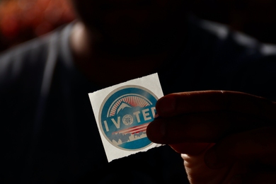 Photo of a person holding "I voted" sticker