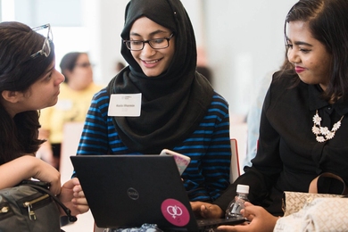 Photo of three women looking at a laptop