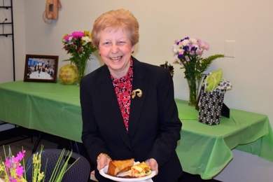 Photo of Maria Bachini, seated, with a plate of food on her lap.