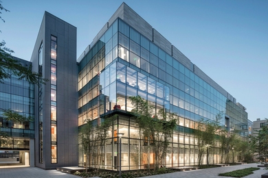 Photo of the Lisa T. Su Building, a modern glass-and-stone building, at twilight. 