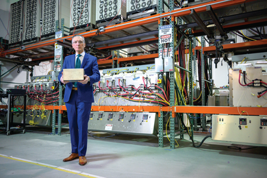 Photo of Donald Sadoway posing with his award in front of a large bank of electronics