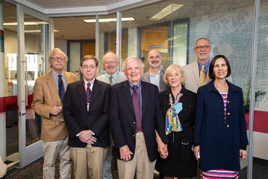 Photo of seven guests posing with Robert Wilhelm in a conference room