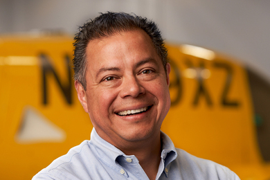 Headshot of Leon Villegas with a yellow Wisk Aero aircraft in the background