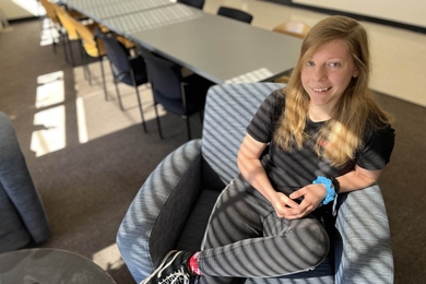 Skylar Dannhoff sitting in chair in sunny lounge area that includes a table with chairs