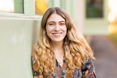Aviva Intveld, leaning against a wall and smiling 