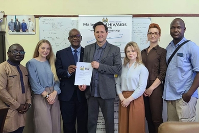 Group photo of seven MIT and Sierra Leone representatives. The two in the center are holding up a piece of paper.