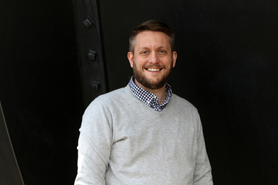 Portrait photo of Benjamin Mangrum standing before a black background