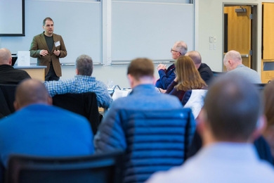 Aleksander Madry stands in front of a whiteboard speaking to a classroom full of participants