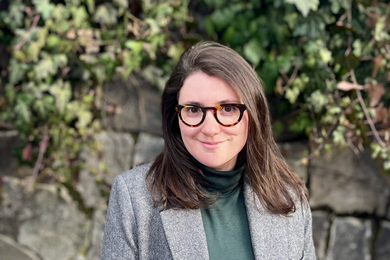 Portrait of Chloe Wittenberg standing in front of a stone wall with ivy creeping down the side