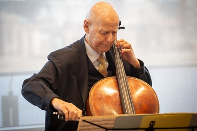 Carlos Prieto sits, playing cello, in a well-lit room