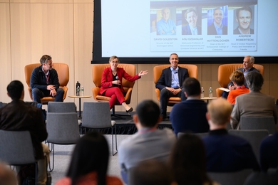 Four AI experts seated on a stage address an audience