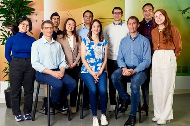 10 people pose, smiling, in two rows