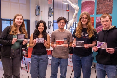 Five MIT students pose holding postcards of their award-winning images.