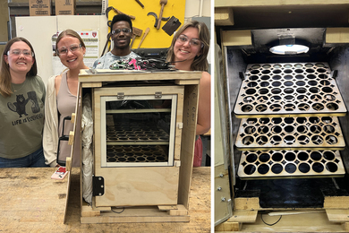 Four students stand in front of wooden laser cut box.