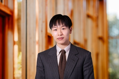 Young man wearing a suit and tie poses against an out-of-focus background