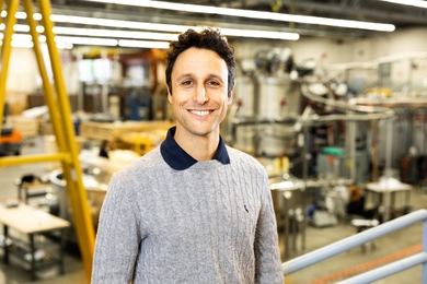 David Cohen-Tanugi stands in front of equipment in a lab at MIT