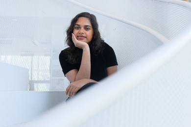 Kimaya Lecamwasam poses on a white spiral staircase, resting her chin in one hand