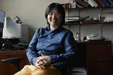 Photo of Sili Deng seated in a small office with shelves behind her
