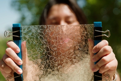 Closeup of Jacqueline Prawira holding up a translucent sheet, with cells that resemble bubble wrap