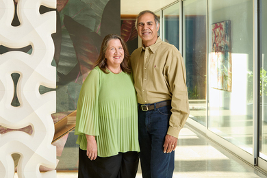 Ana Méndez and Rajeev Jayavant pose together in a corridor filled with artwork