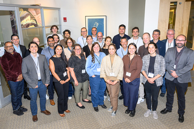 27 people stand for a group photo in an office