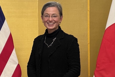 Christine Pilcavage poses standing between an American flag and a Japanese flag