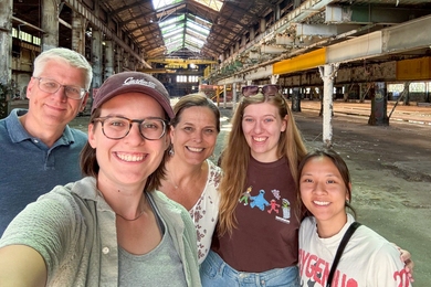 Sara Jex takes a selfie with four family members inside a large, abandoned industrial warehouse