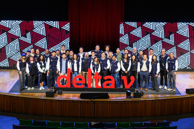 About 30 Demo Day participants are on stage wearing custom letterman jackets.